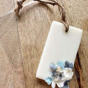 Placa de cera perfumada azul com flores estabilizadas e saco transparente para lembrança de casamento, batizado ou comunhão